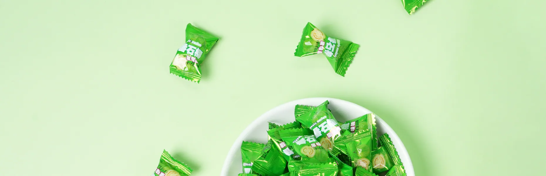 Wrapped Hongyuan guava candies scattered around a white dish